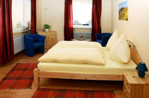 a bedroom with two beds and two blue chairs at Gasthaus Ochsen in Ortenberg