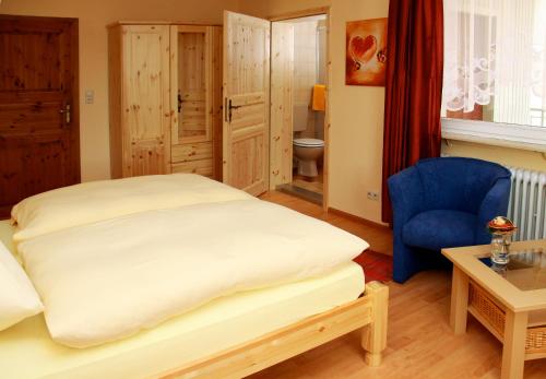 a bedroom with a large bed and a blue chair at Gasthaus Ochsen in Ortenberg