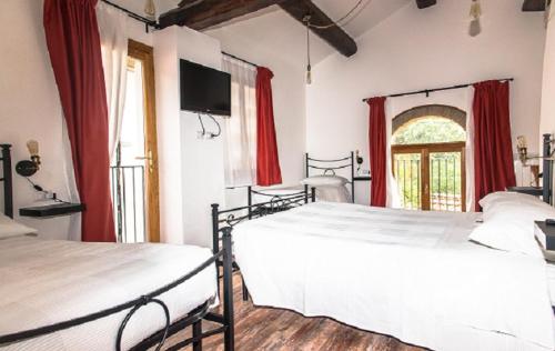 2 camas en un dormitorio con cortinas rojas y ventana en B&B Il Pittore, en Borgo San Lorenzo