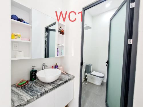 een badkamer met een wastafel en een glazen douchedeur bij Sunrise House in Hàm Tân