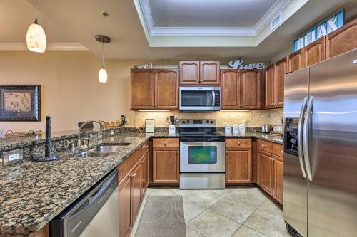 a kitchen with wooden cabinets and stainless steel appliances at Beachfront Dauphin Island Condo Pool Access! in Dauphin Island