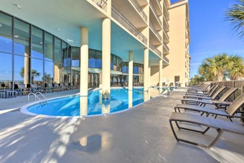 a large building with a swimming pool and chairs at Beachfront Dauphin Island Condo Pool Access! in Dauphin Island