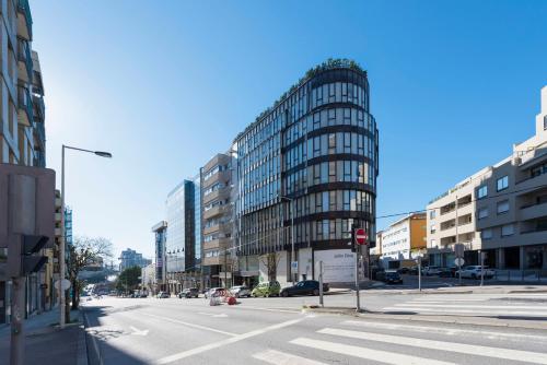 an empty city street with a tall glass building at DOISPONTOZERO Júlio Dinis in Porto