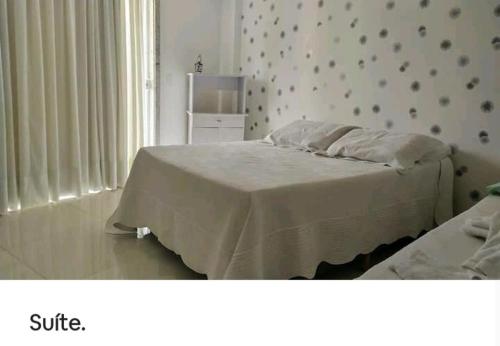 a bedroom with a bed with white sheets and a wall at Apto da Dê - Centro de Venda Nova do Imigrante ES in Venda Nova do Imigrante