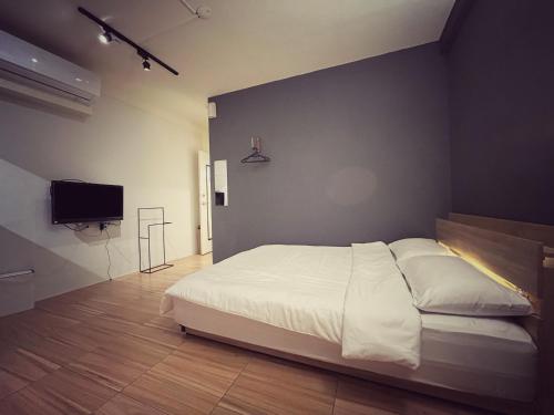 a bedroom with a white bed and a flat screen tv at 東海平行陸貳民宿English Friendly in Longjing