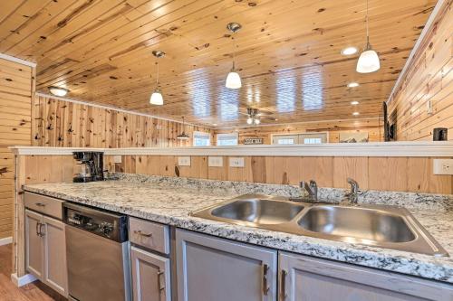 a kitchen with a stainless steel sink and wooden walls at Cozy Elmira Cabin with Deck, 23 Mi to Slopes! 