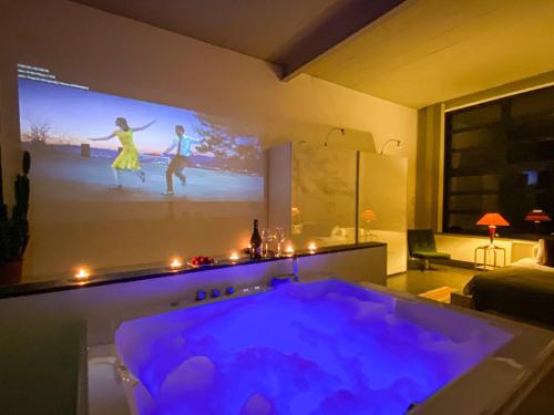 un salon avec une baignoire et un écran de projection dans l'établissement Comenstay Brussels, à Bruxelles
