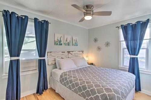 a bedroom with a bed with blue curtains and a ceiling fan at Grand Junction Vacation Rental with Fire Pit! in Grand Junction
