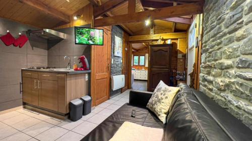 een woonkamer met een bank en een keuken bij Au chalet d'Isa in Havelange