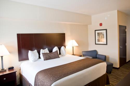 a hotel room with a large bed and a chair at Cobblestone Inn & Suites -Clarinda in Clarinda