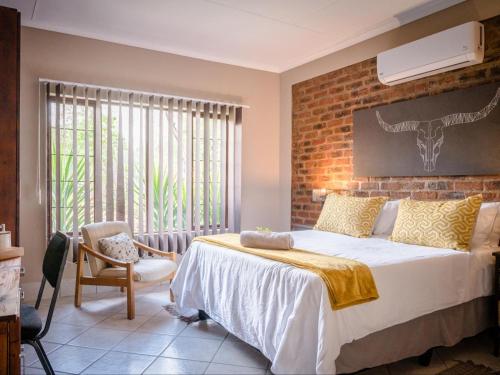a bedroom with a bed and a brick wall at Bosveld Villa in Marloth Park