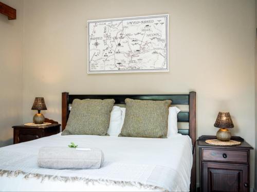 a bedroom with a bed and two night stands with lamps at Bosveld Villa in Marloth Park