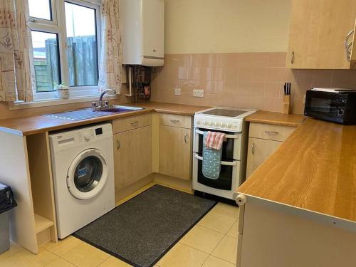 a kitchen with a washing machine and a sink at BridgeCity Spacious Cottage in the Heart of Basingstoke in Worting