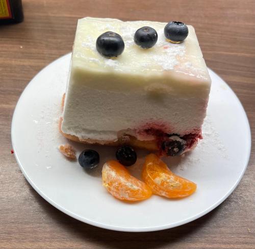 a piece of cake on a plate with blueberries and oranges at Pensiunea Deceneu in Slănic