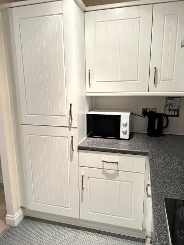 a kitchen with white cabinets and a microwave at Next-Stop Haven in Harlow