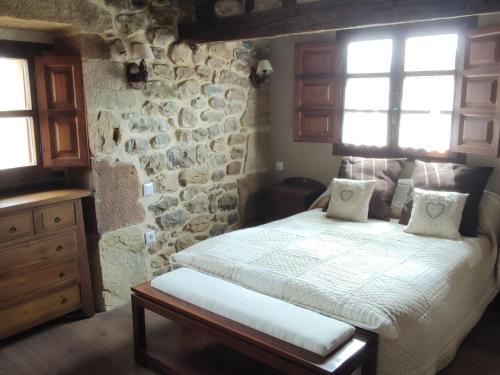 1 dormitorio con cama y pared de piedra en El Limonero, en Arenas de Iguña
