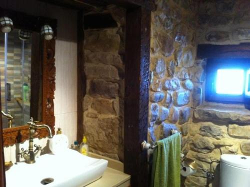 baño con lavabo y pared de piedra en El Limonero, en Arenas de Iguña