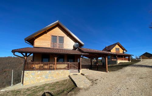 a wooden house with a porch and a balcony at Zlatar Lake Hill in Nova Varoš