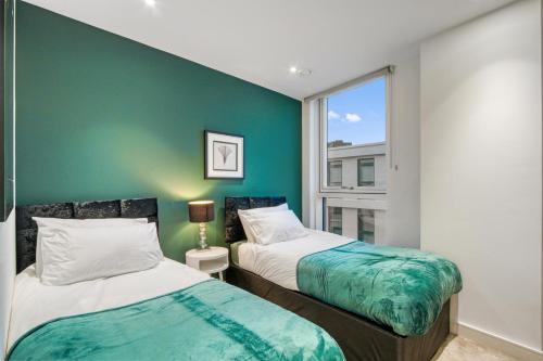 two beds in a room with a green wall at Contemporary and Stylish 2 Bed in Nine Elms in London