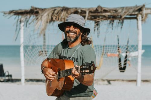 a man playing a guitar on the beach at Hotel Encanto Holbox Beach Front in Holbox Island
