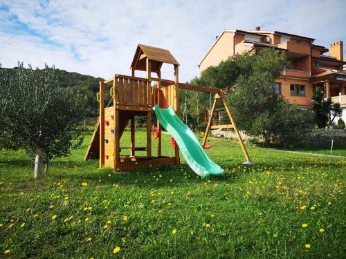 un parque infantil con un tobogán en un campo de césped en Apartments Melita, en Supetarska Draga