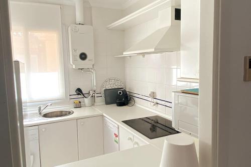 a white kitchen with white cabinets and a sink at Novo Sancti Petri, La Barrosa, 2 Beds Room Apartamento by Chiclana Dreams in Chiclana de la Frontera
