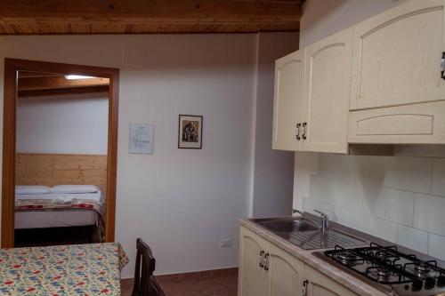 a kitchen with white cabinets and a sink and a bed at Agriturismo Dai Mori in Isola del Piano