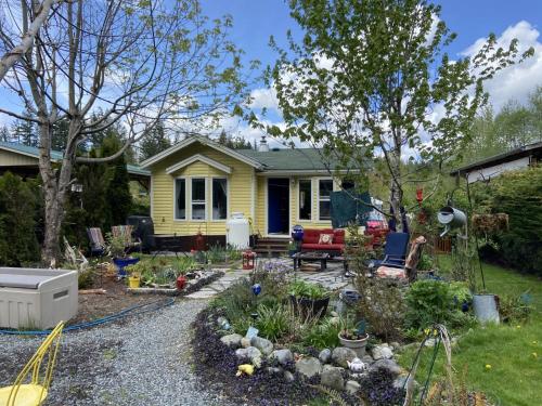 un jardín frente a una casa amarilla en Beaver Lake Resort Site #36 en Lake Cowichan