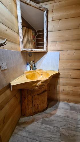 ein Badezimmer mit einem hölzernen Waschbecken und einem Spiegel in der Unterkunft Cabana Păstrăvului in Izvoarele Sucevei