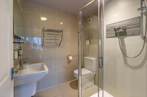 a bathroom with a shower and a toilet and a sink at Holly Lodge Guest House with FREE off site health club in Windermere
