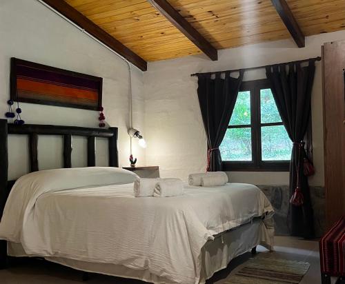 a bedroom with a bed with white sheets and a window at Cabaña tierra verde in Yala