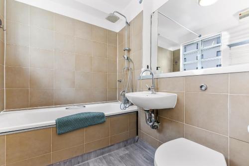 a bathroom with a sink and a toilet and a bath tub at Spacious 2 Bedroom Apartment in Ealing Broadway in Ealing