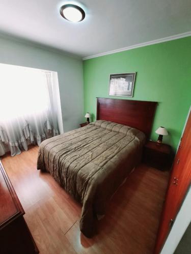 1 dormitorio con cama y pared verde en Torre Jacarandá de Buenos Aires en Buenos Aires