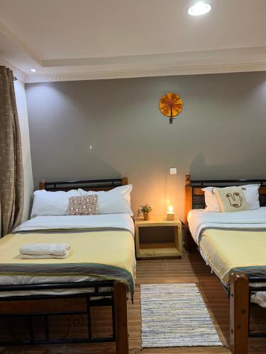 sypialnia z 2 łóżkami i zegarem na ścianie w obiekcie Masai Heritage Guesthouse w mieście Ololaimutiek