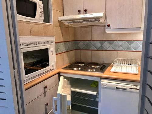 une petite cuisine avec une cuisinière et un micro-ondes dans l'établissement Studio rénové à Tignes, proche pistes, wifi gratuit - FR-1-449-1, à Tignes