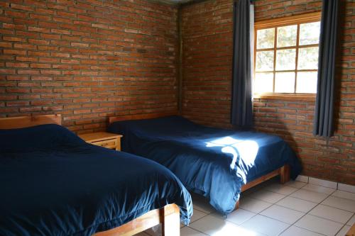 two beds in a room with a brick wall at Cabaña Familiar en el Bosque Parque La Pirámide 