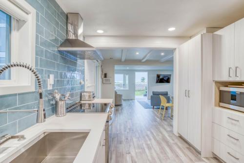 a kitchen with white cabinets and blue tiles on the wall at The Weather Gauge in Rockaway Beach