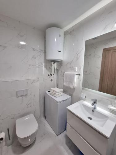 a white bathroom with a toilet and a sink at Master Quart modern apt. 27 in Podgorica