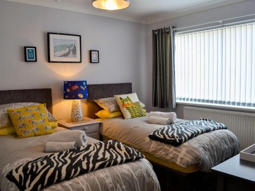 a bedroom with two beds with zebra pillows on them at Scarborough Rose Apartment in Scarborough