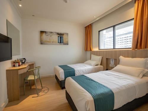 a hotel room with two beds and a television at Floresta Hotel Chinatown in Kuala Lumpur