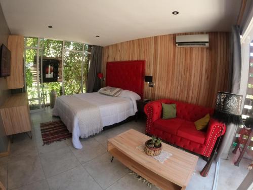 1 dormitorio con 1 cama y 1 sofá rojo en Departamento con parque a metros del mar en Ostende