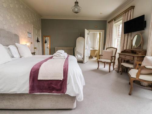 een slaapkamer met een groot wit bed en een piano bij The Stables and West Wing in York