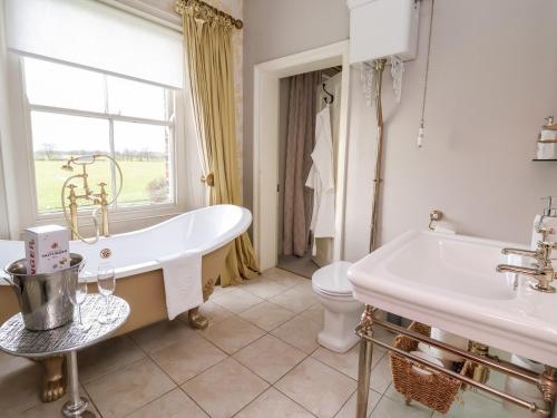 a bathroom with a tub and a toilet and a sink at The Stables and West Wing in York