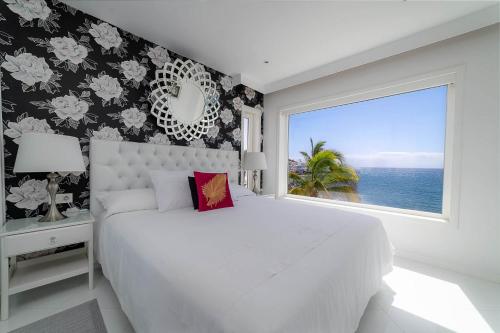 a bedroom with a large white bed and a window at Lani's Suites de Luxe - Adults Only in Puerto del Carmen