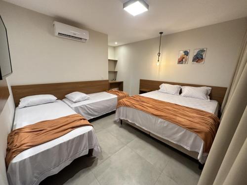 Habitación con 2 camas en una habitación en Pousada WOOD SUITES, en São Miguel do Gostoso