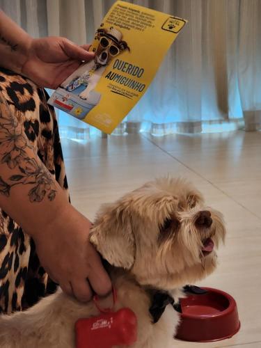 a woman is petting a small dog on a leash at Paradiso Corporate in Cabo Frio