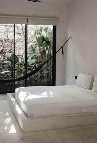 a bedroom with a white bed and a large window at Villa 16Tulum in Tulum