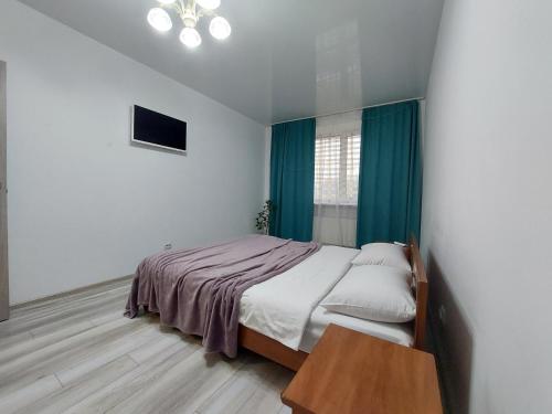 a bedroom with a bed with green curtains and a table at Яровиця 11 in Lutsk