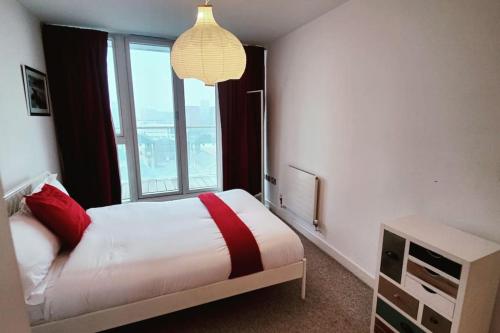 sypialnia z łóżkiem i dużym oknem w obiekcie Custom House Apartments w Londynie