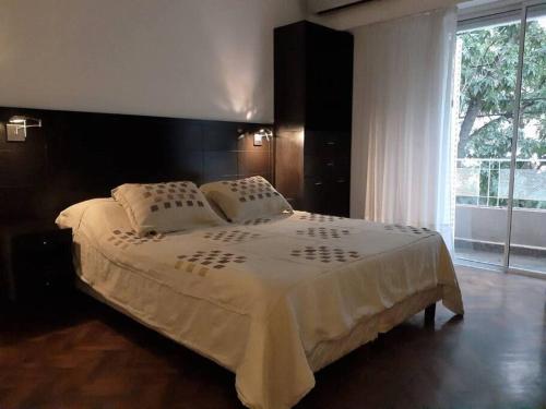 a bedroom with a large bed with a large window at Depto para descansar y disfrutar in Buenos Aires
